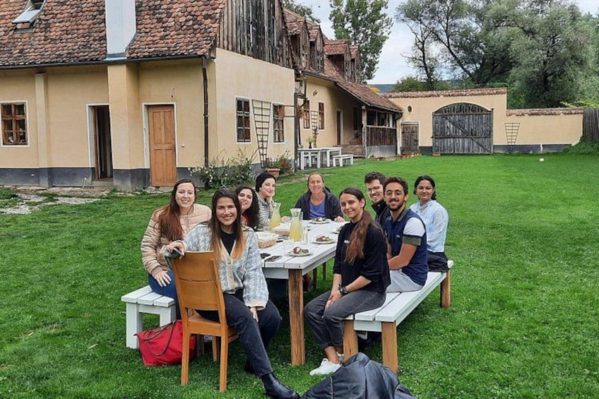 A group of people sitting at a table outdoors with a house in the background. 2