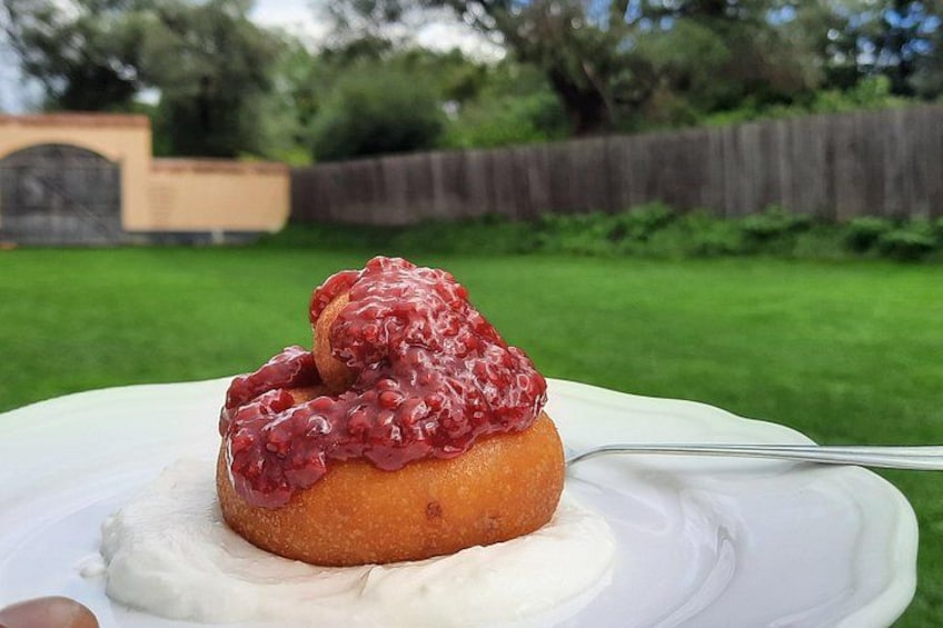 A dessert on a white plate with a fork, set against a backyard with a wooden fence and greenery. 3