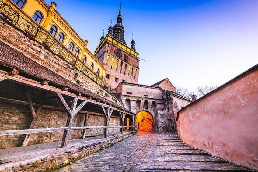 A cobblestone street leading to a historic building with a clock tower. 1