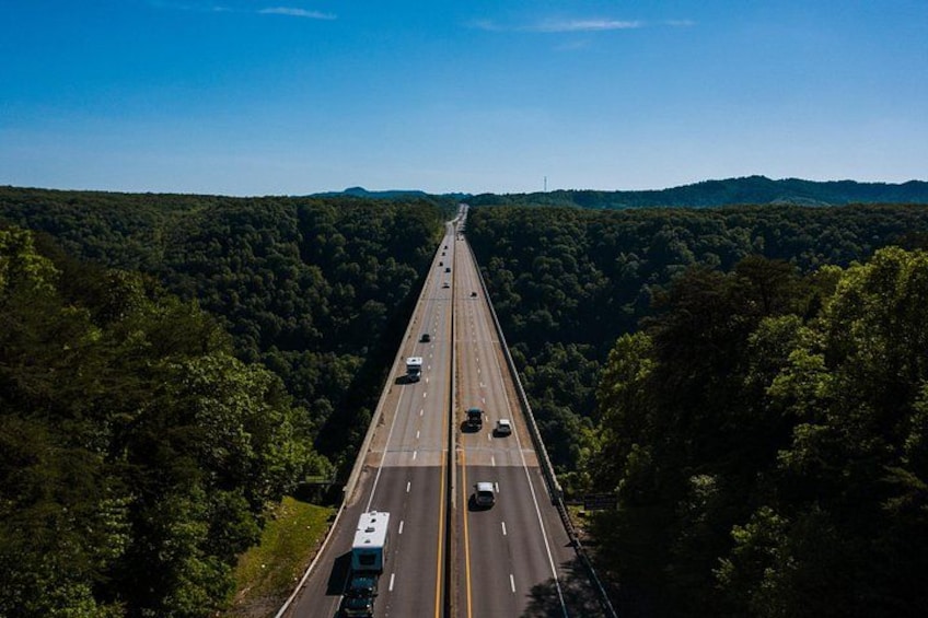 Eine mehrspurige Autobahn, umgeben von dichtem Wald, unter blauem Himmel. 3