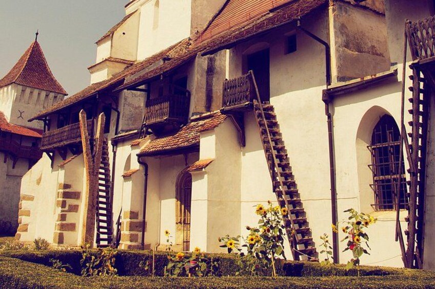 Un bâtiment historique doté d’un toit à forte pente, d’escaliers en bois et de fenêtres en arc de cercle. 1