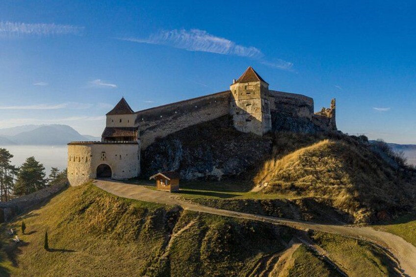 Un château historique perché sur une colline, avec une tour, un petit bâtiment et un sentier. 2