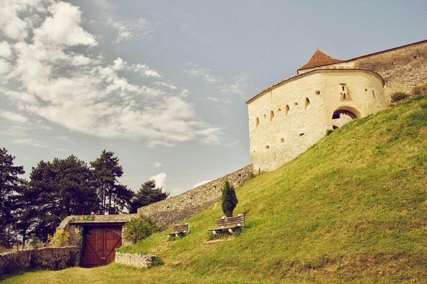 Un bâtiment historique en pierre, doté d’une tour ronde, d’une colline verdoyante et d’une structure en bois. 5