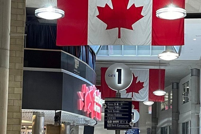 A travel information board with a red maple leaf and a sign indicating Gate 1. 3
