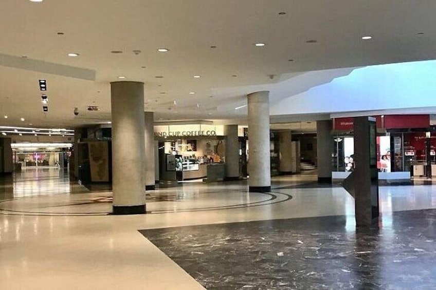 A spacious indoor area with a coffee shop, large pillars, and a polished floor. 4