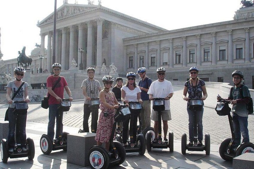 Een groep mensen op Segways voor een klassiek gebouw met zuilen. 4