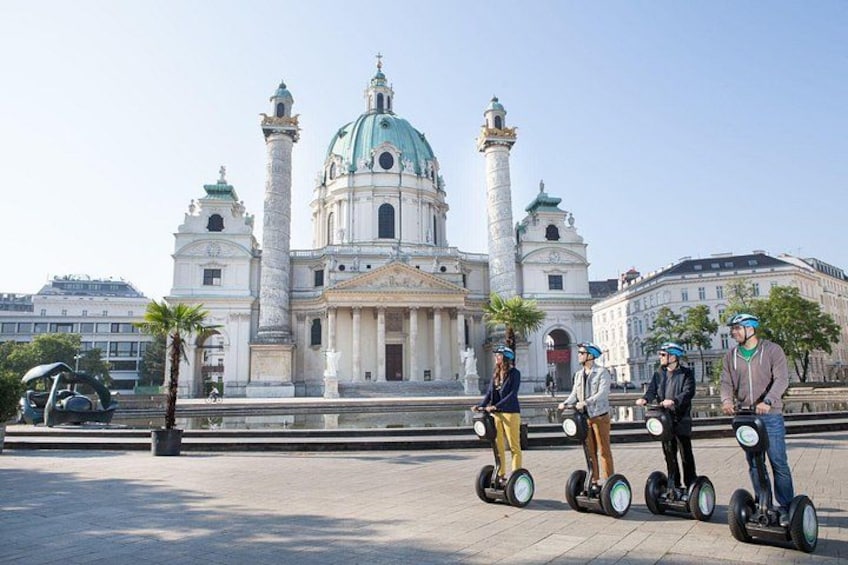 Een groep mensen op segways voor een historisch gebouw met een koepel en kolommen. 2