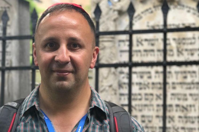 A person standing in front of a wall with Hebrew text. 2