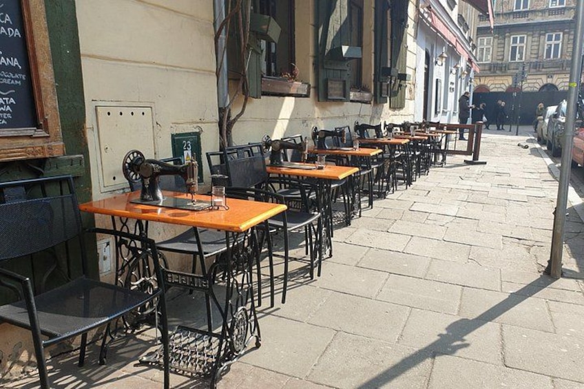 Outdoor cafe tables and chairs, a street, and buildings in the background. 4