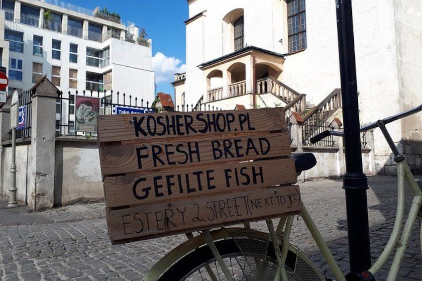 A wooden sign on a bicycle, advertising a kosher shop with fresh bread and gefilte fish, located at Esterly Street. 3