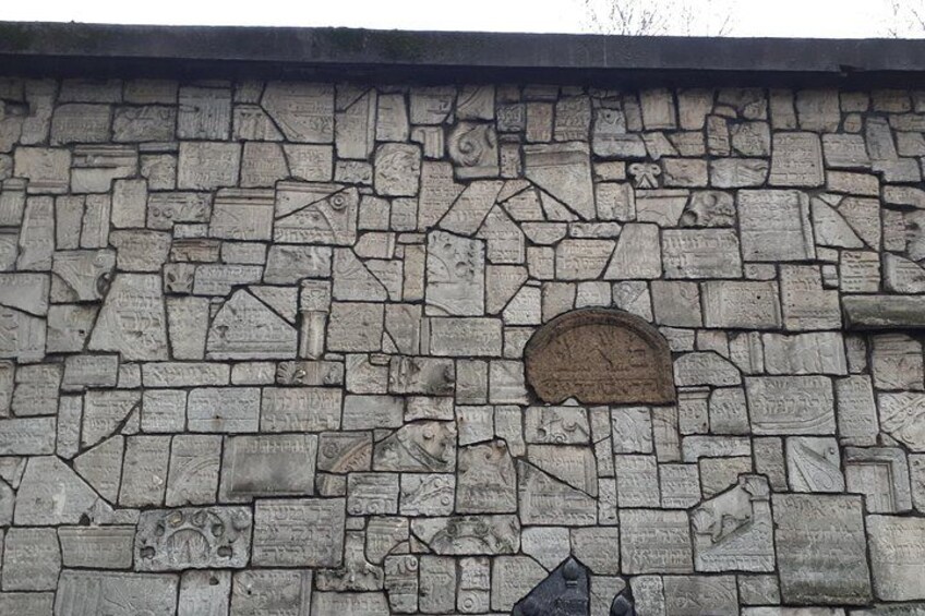 A stone wall with carved symbols and a circular emblem. 5