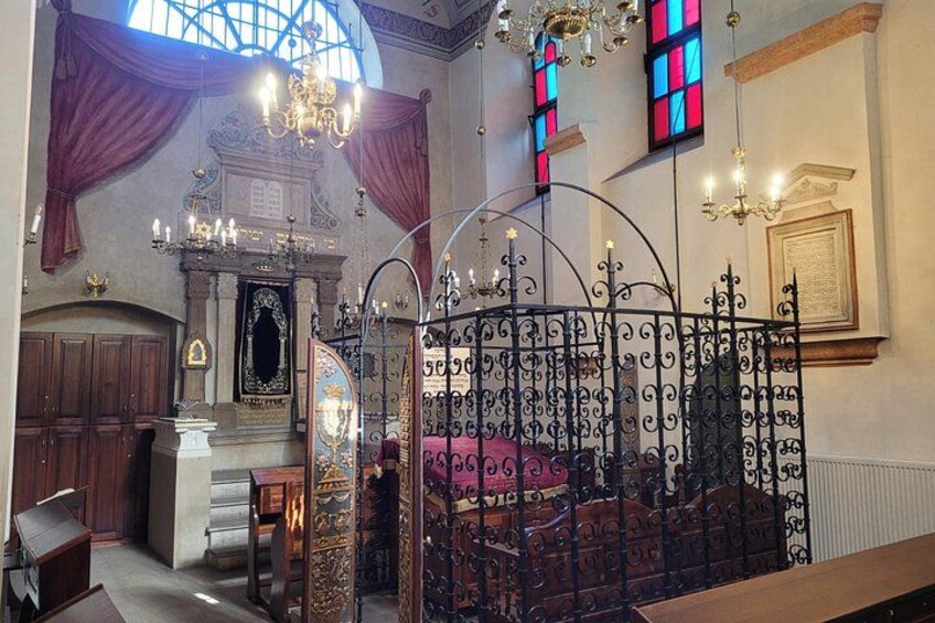 An ornate church interior with stained glass windows, a chandelier, and a wrought iron fence. 3