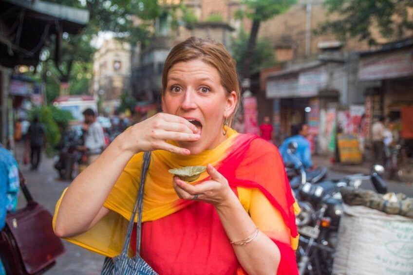 Una persona comiendo en una calle urbana, con tiendas y motocicletas de fondo. 3