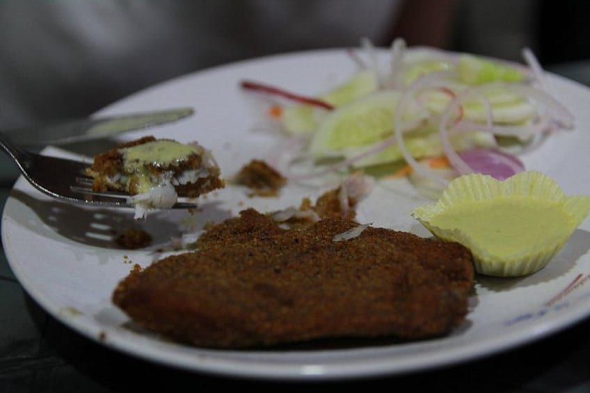 A plate with a piece of breaded meat, a fork, and a salad with sliced vegetables. 3