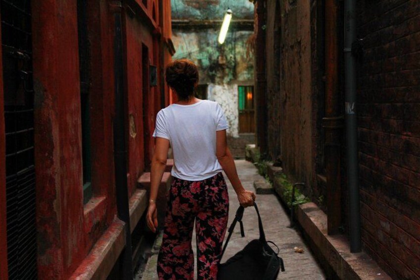 Una persona caminando por un callejón estrecho con paredes de ladrillo y una puerta roja. 2