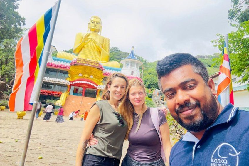 A large golden Buddha statue, a temple with a colorful roof, and flags. 2