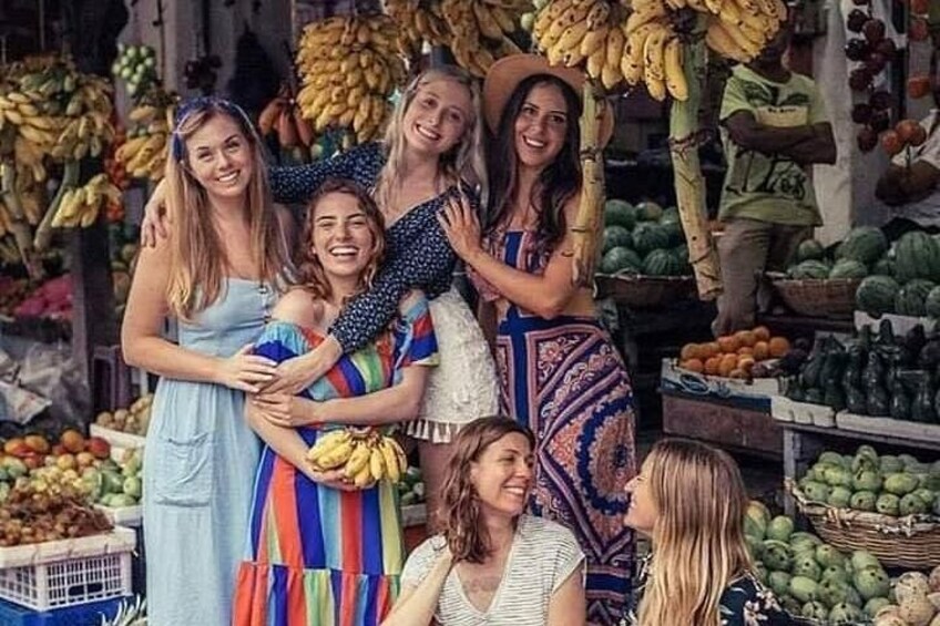 A group of people at a market with various fruits and vegetables on display. 1