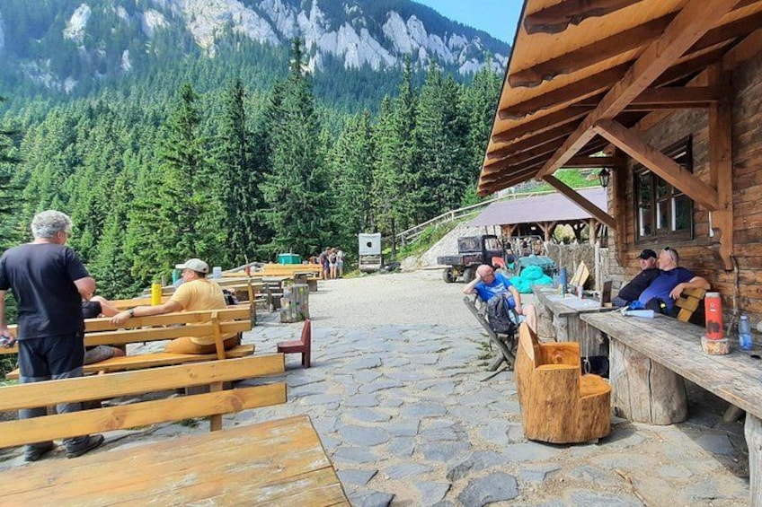 Een houten terras met banken en tafels, omgeven door een bebost berglandschap. 5
