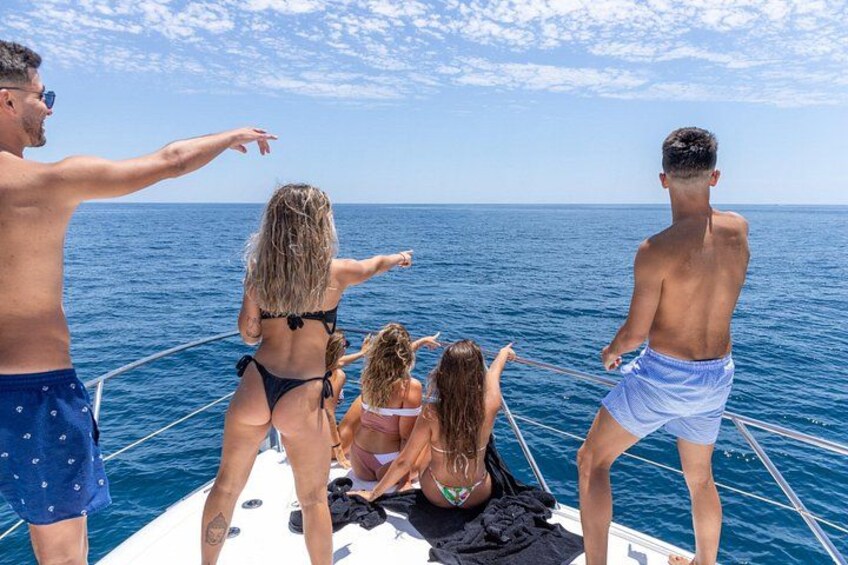 A boat with people on deck, ocean, and clear sky. 5