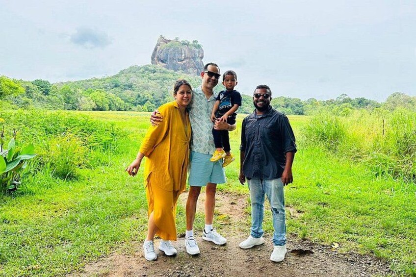 A family of four in a grassy field with a large rock formation in the background. 3