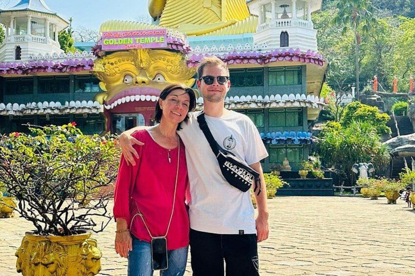A couple standing in front of a colorful temple with a golden statue. 4