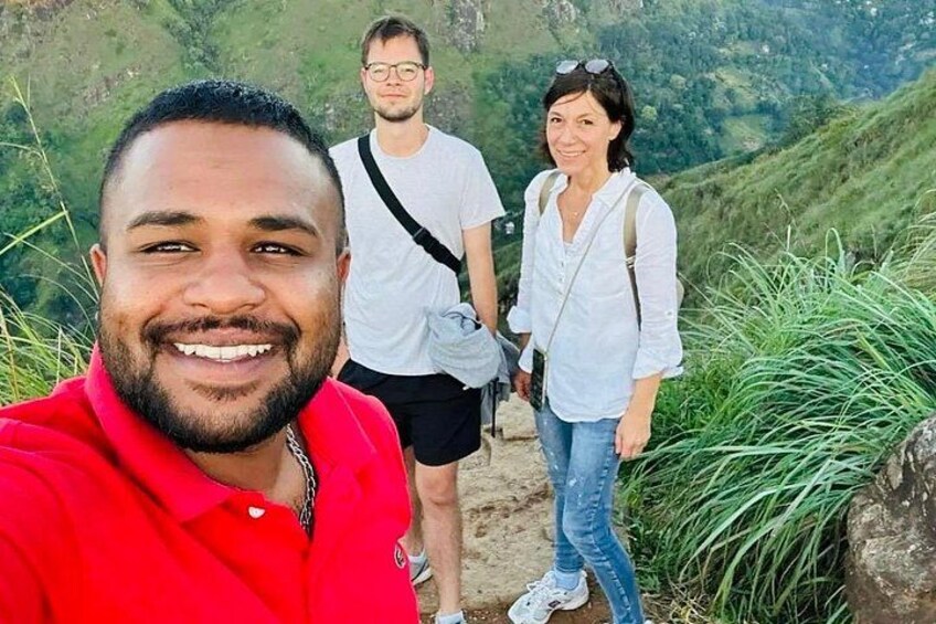 A person in a red shirt taking a selfie with two others in a mountainous area. 5