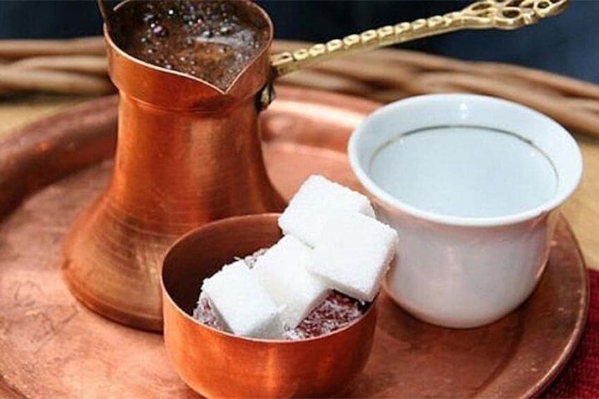 A copper teapot, a small bowl of sugar cubes, and a cup of water on a tray. 5