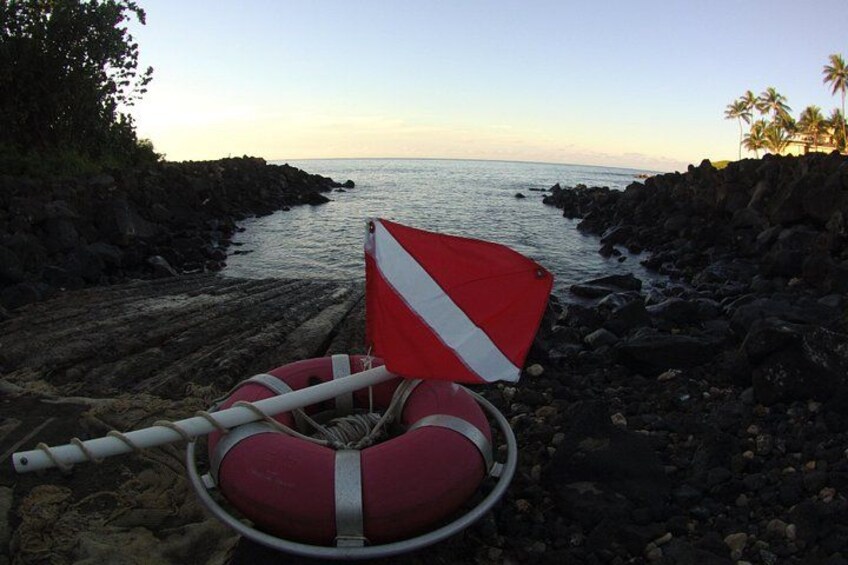 A rocky shoreline with a red and white life buoy and a white rope. 2