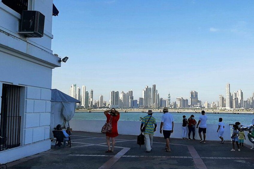Vandkant med folk, der står og sidder og ser ud over byens skyline. 4