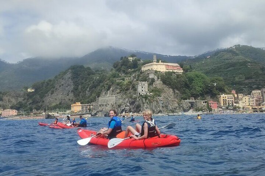 People kayaking on a calm sea with a coastal town and a castle in the background. 4