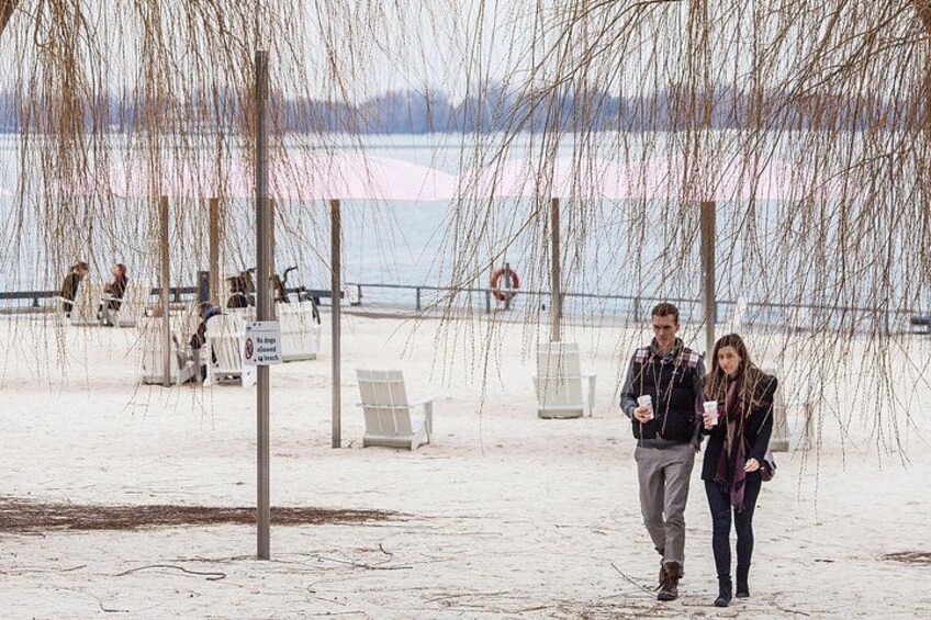A couple walking on a snow-covered beach with a lake in the background. 3