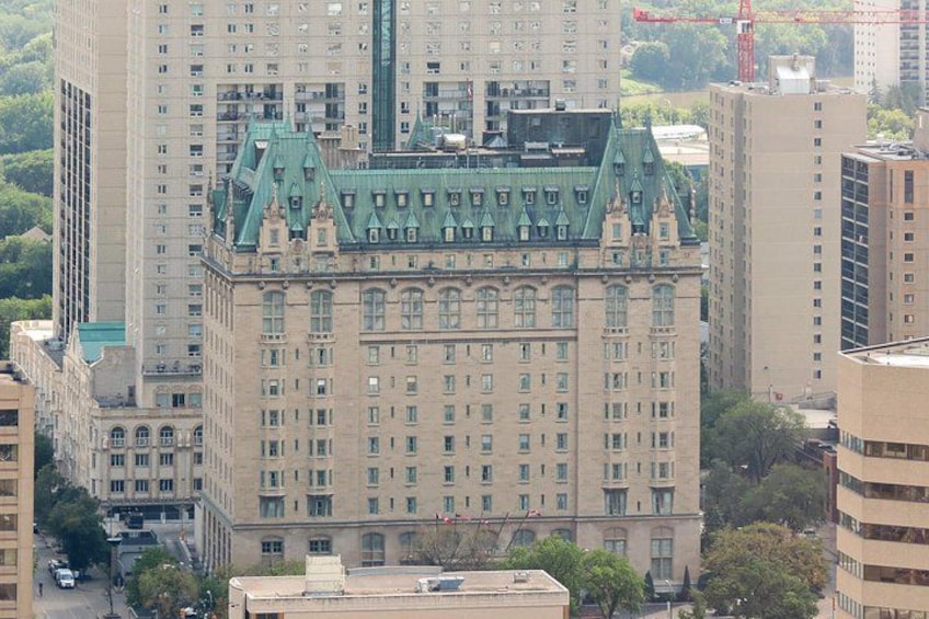 A historic building with a green roof and multiple windows, surrounded by modern high-rise buildings. 4