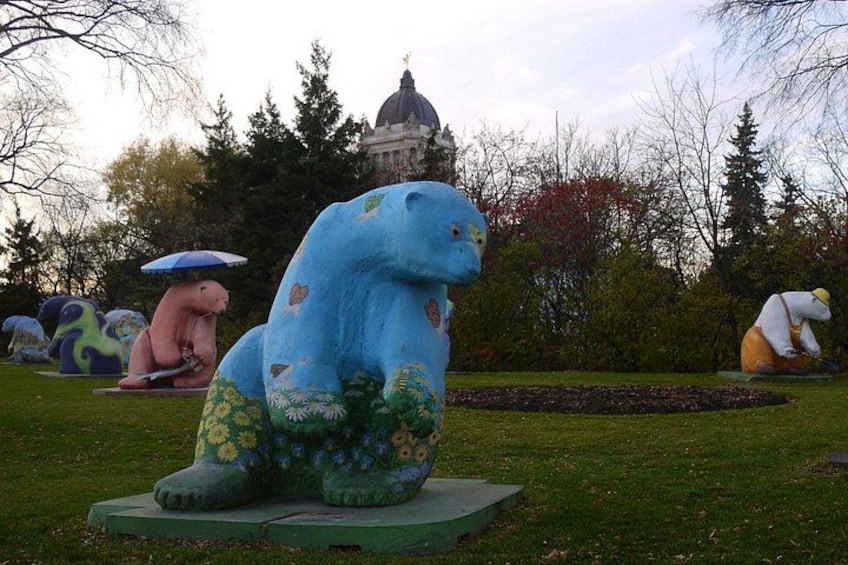A large blue elephant sculpture in a park with other animal sculptures and a dome-shaped building in the background. 3