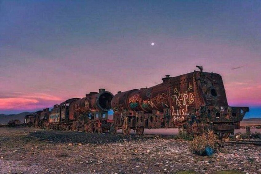 A derelict train with graffiti, set against a twilight sky. 1