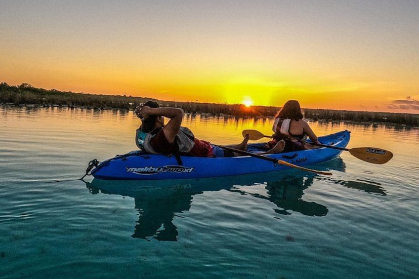 Due persone che fanno kayak su un'acqua calma al tramonto. 2