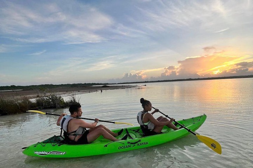 Due persone che fanno kayak su un'acqua calma al tramonto. 5