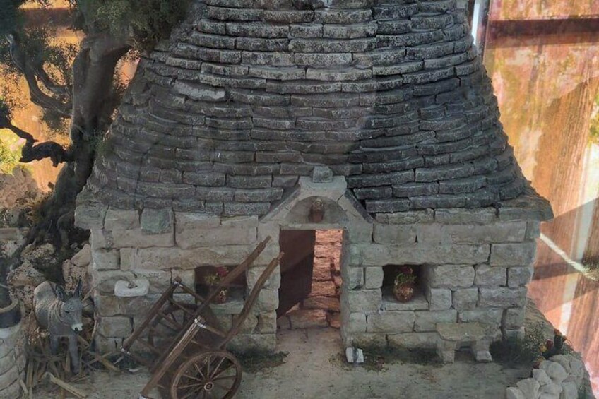 Una estructura de piedra con techo cónico, un carro de madera y un pequeño acceso. 4
