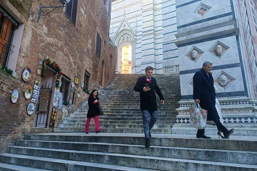 People walking up a set of stone steps in an urban area with historical architecture. 4