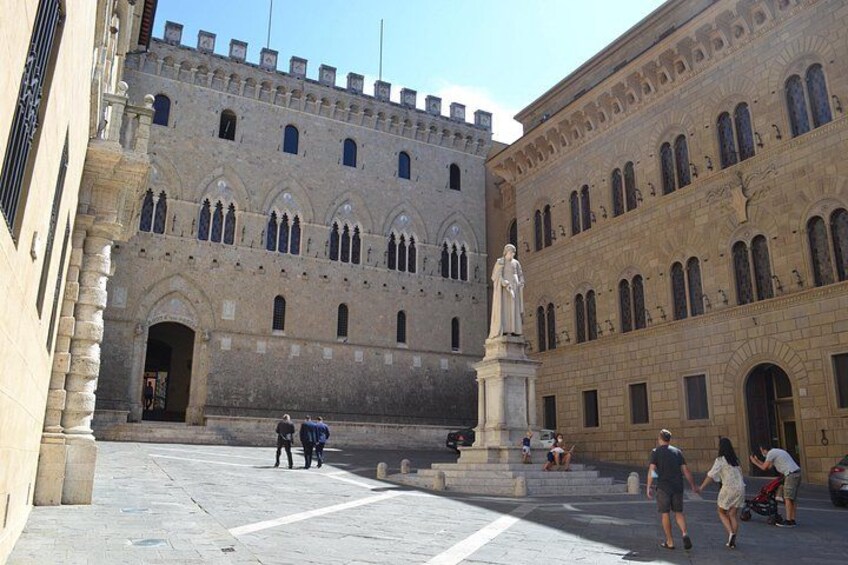 A historic building with arched windows and a statue in the courtyard. 3
