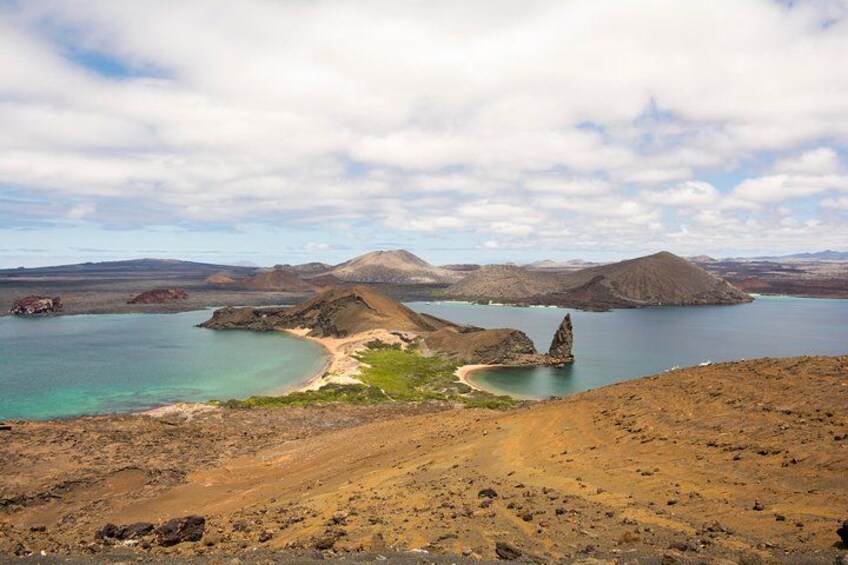 Un paisaje costero con cielo despejado, una playa de arena y una isla rocosa. 1