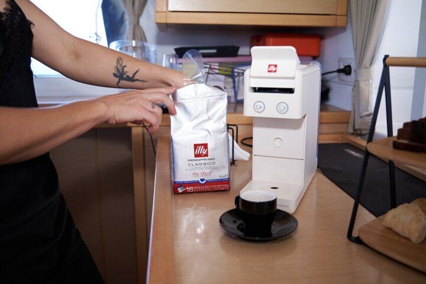 A person preparing coffee with an Illy coffee machine and a bag of Illy coffee. 3