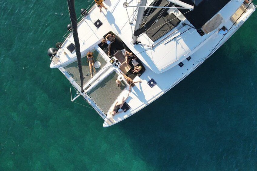 A white sailboat with a deck area, a mast, and a person standing at the bow. 2