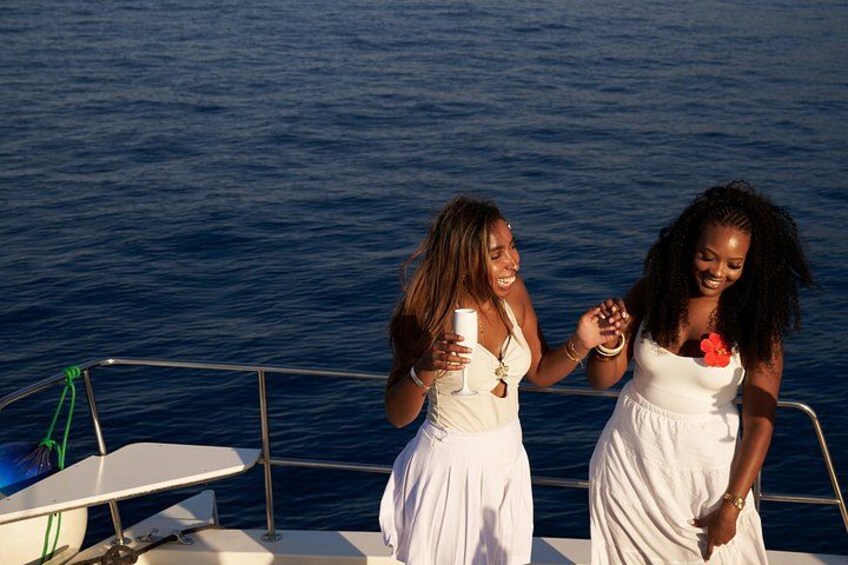 Two women on a boat, holding hands, with a body of water in the background. 3