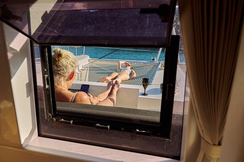 A window with a view of a pool and a person relaxing on a lounge chair. 5