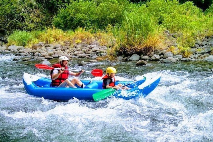 Two people kayaking on a river surrounded by greenery. 3