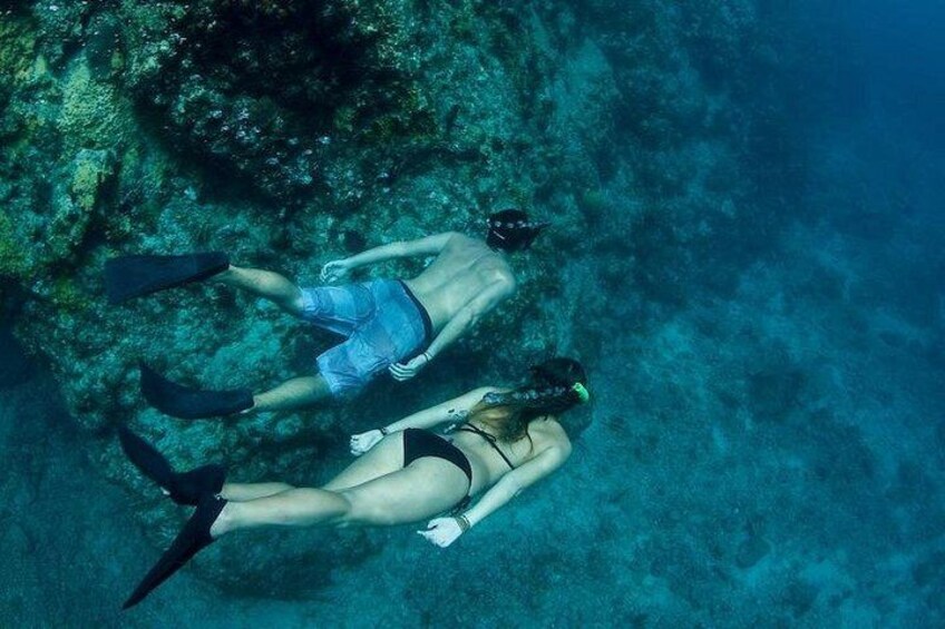 Twee mensen snorkelen onderwater, omringd door zeeleven en koraalformaties. 2