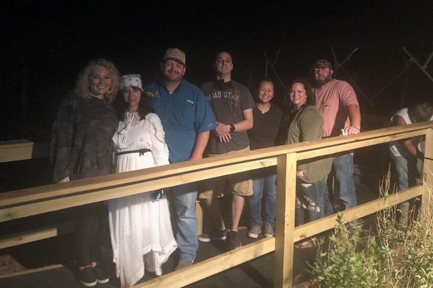 Un grupo de personas de pie sobre un puente de madera en la noche. 5