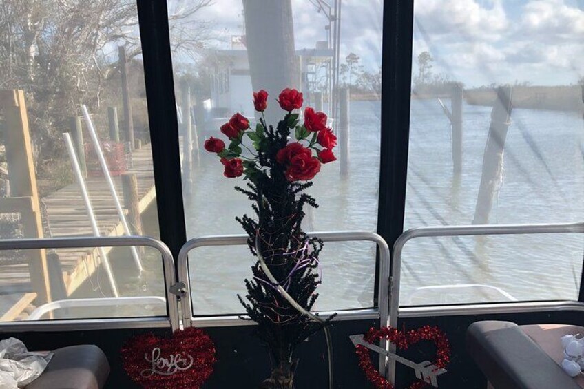 A window with a vase of red roses, a heart-shaped decoration, and a railing. 2