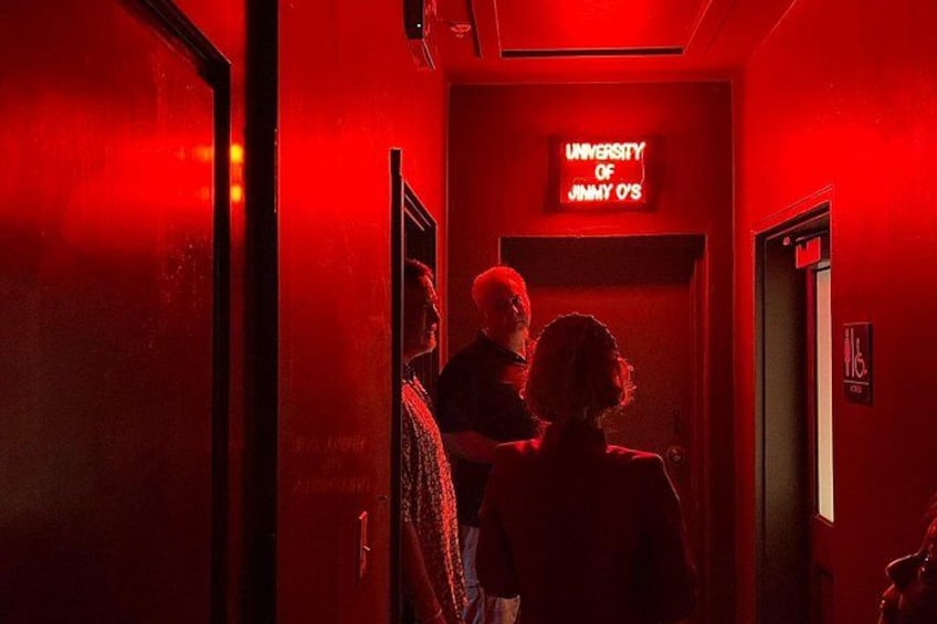 Un corridoio illuminato da luci rosse con un cartello che riporta la scritta 'University of Jimmy O's'. 3