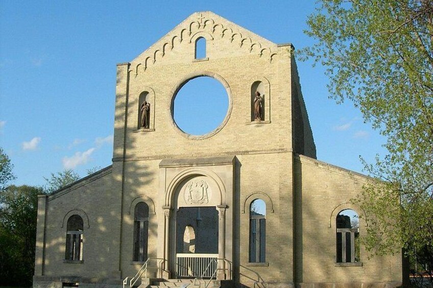 Eine Kirche mit einem großen Rundfenster, gewölbten Eingängen und einem Glockenturm. 3
